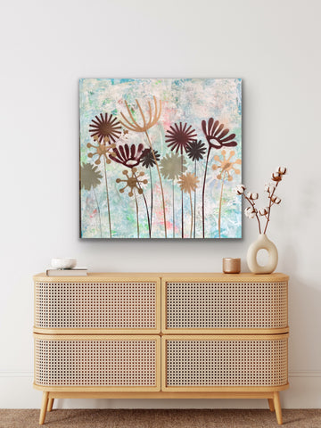 Einrichtungsbeispiel im natürlichen Boho-Stil: Das abstrakte Blumengemälde 'Summertime' hängt rahmenlos über einer hellen Rattan-Kommode. Daneben steht eine skulpturale Vase mit Baumwollzweigen.