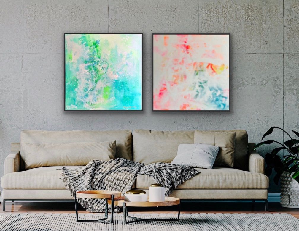 Einrichtungsbeispiel im Industrial-Style: Zwei quadratische, abstrakte Gemälde hängen als Duo in schwarzen Rahmen an einer nackten Betonwand über einem beigefarbenen Sofa. Das linke Bild ist grün-blau, das rechte Bild ('Summer') ist weiß-bunt.