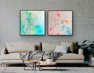 Einrichtungsbeispiel im Industrial-Style: Zwei quadratische, abstrakte Gemälde hängen als Duo in schwarzen Rahmen an einer nackten Betonwand über einem beigefarbenen Sofa. Das linke Bild ist grün-blau, das rechte Bild ('Summer') ist weiß-bunt.