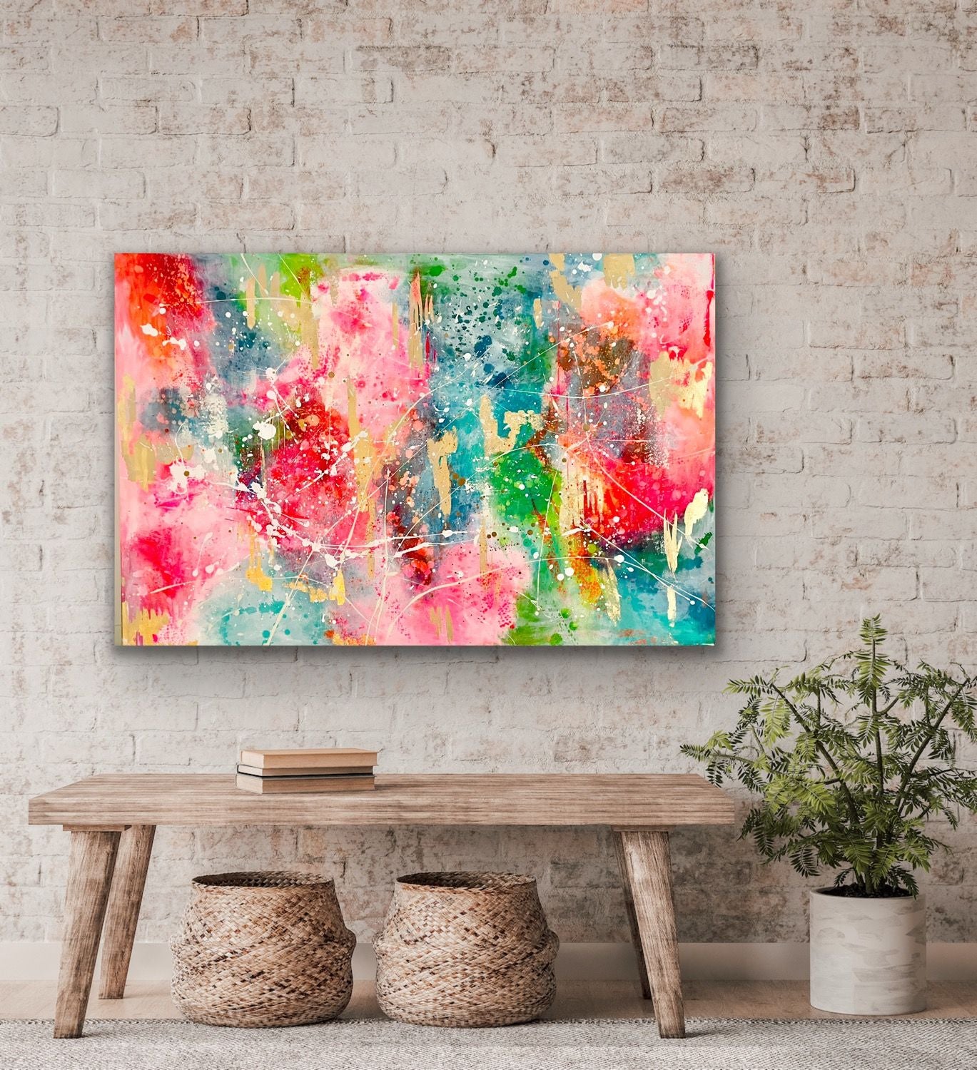 Einrichtungsbeispiel: Das große, farbenfrohe und abstrakte Gemälde hängt im Querformat an einer hellen Backsteinwand über einer rustikalen Holzbank. Auf dem Boden stehen geflochtene Körbe und eine Pflanze.