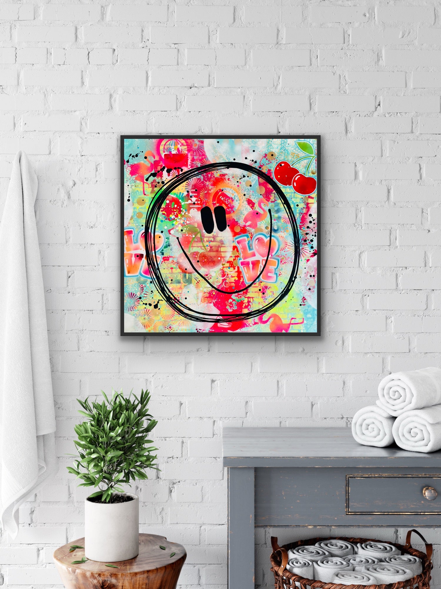 Raumansicht: Das fröhliche Smiley-Kunstwerk "Cherry Smile" von Künstlerin Diana Gumz hängt als moderner Kunstdruck gerahmt an einer hellen Wand über einer Kommode.