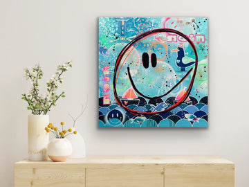 Mockup einer Wohnzimmer-Einrichtung mit dem maritimen Wandbild 'Küsten Smile'. Das farbenfrohe Gemälde von Diana Gumz hängt über einem hölzernen Sideboard mit weißen Vase.
